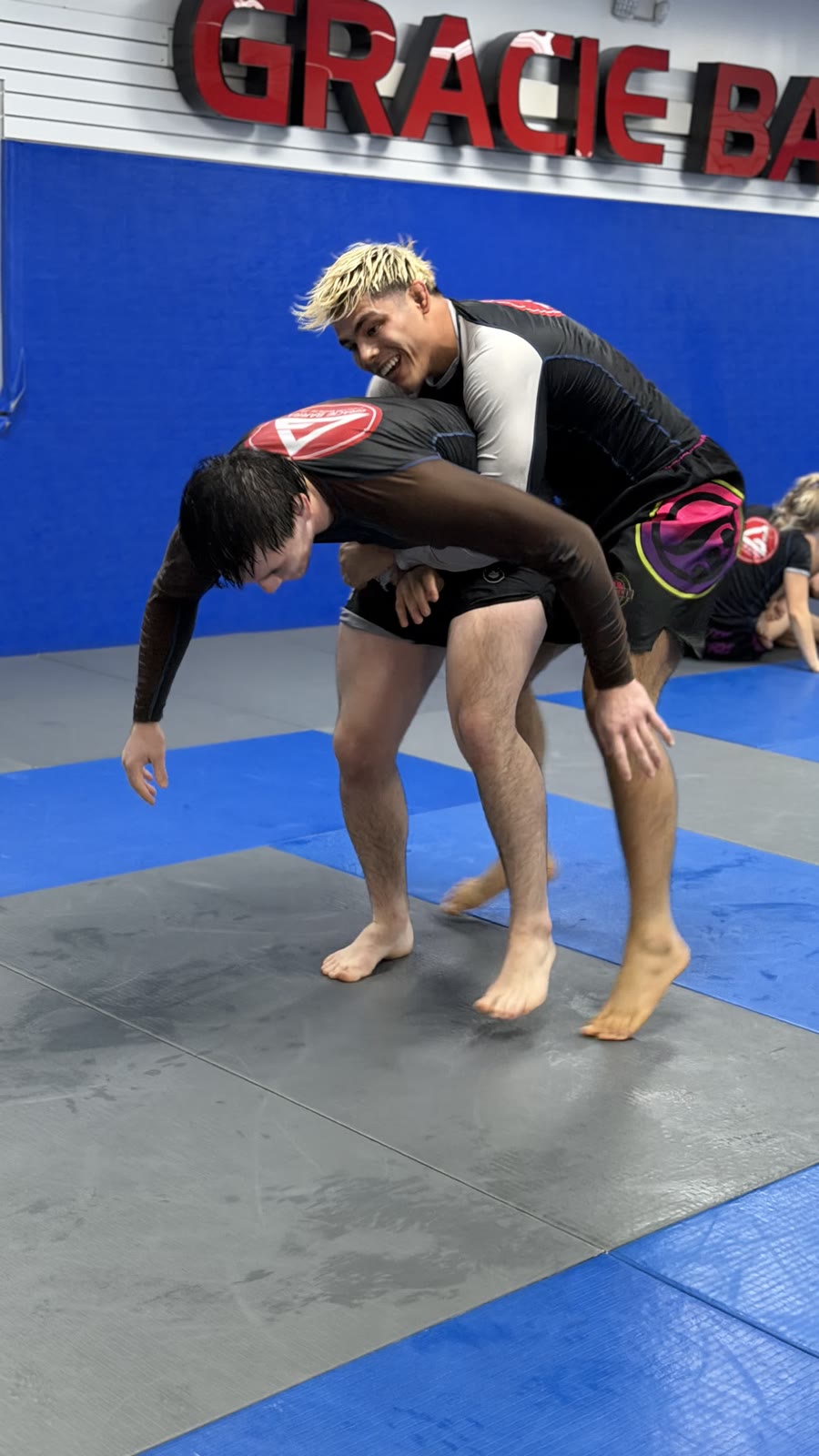 Two adults practicing a rear body lock during No-Gi jiu-jitsu class at Gracie Barra Westchase in Houston.