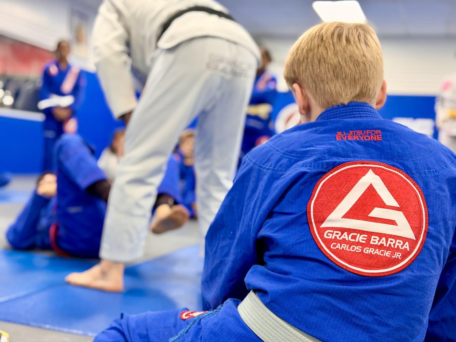 Older Kids BJJ Class Instruction – Gracie Barra Westchase Older youth student in a blue gi watching class instruction at Gracie Barra Westchase in Houston