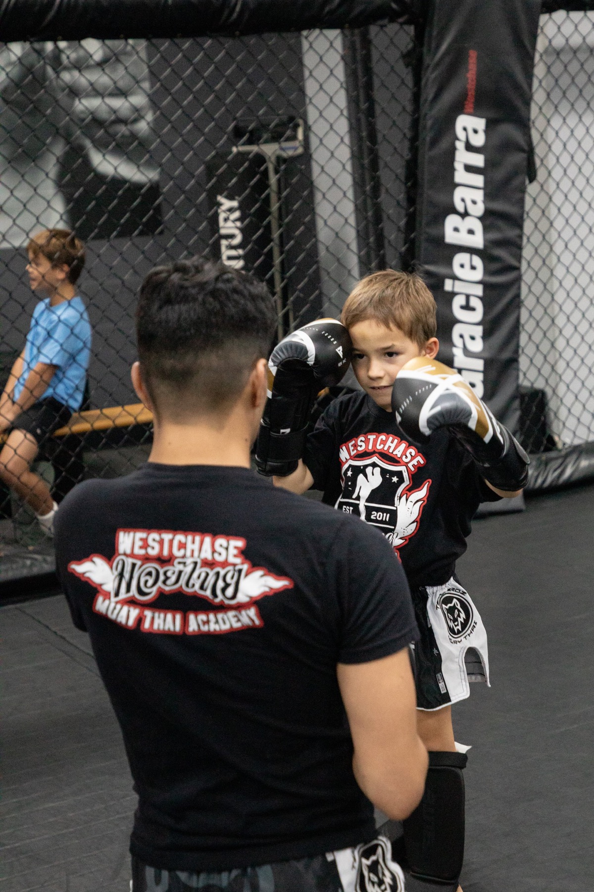 Young kickboxing student practicing a boxing guard with a coach at Gracie Barra Westchase in Houston